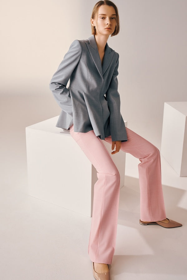 Model is wearing a tailored gray blazer and pink straight-leg pants.