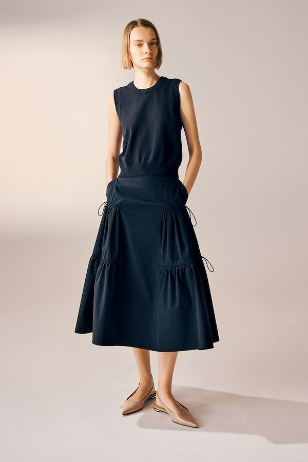 Model is wearing a black sleeveless knit top with a gathered midi skirt.