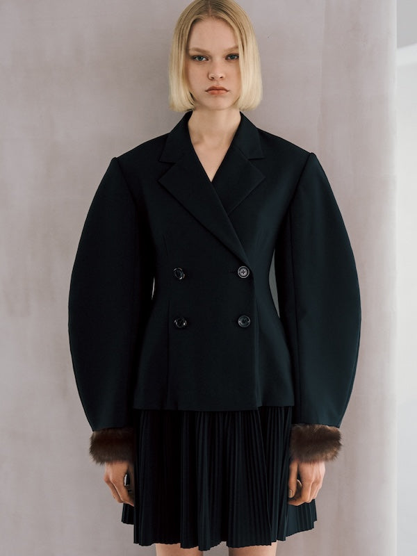 The model is wearing a black jacket and a black skirt.