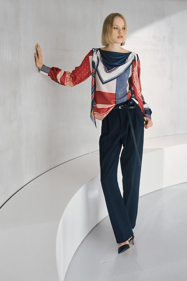 The model is wearing a blue and white patterned top and navy pants.