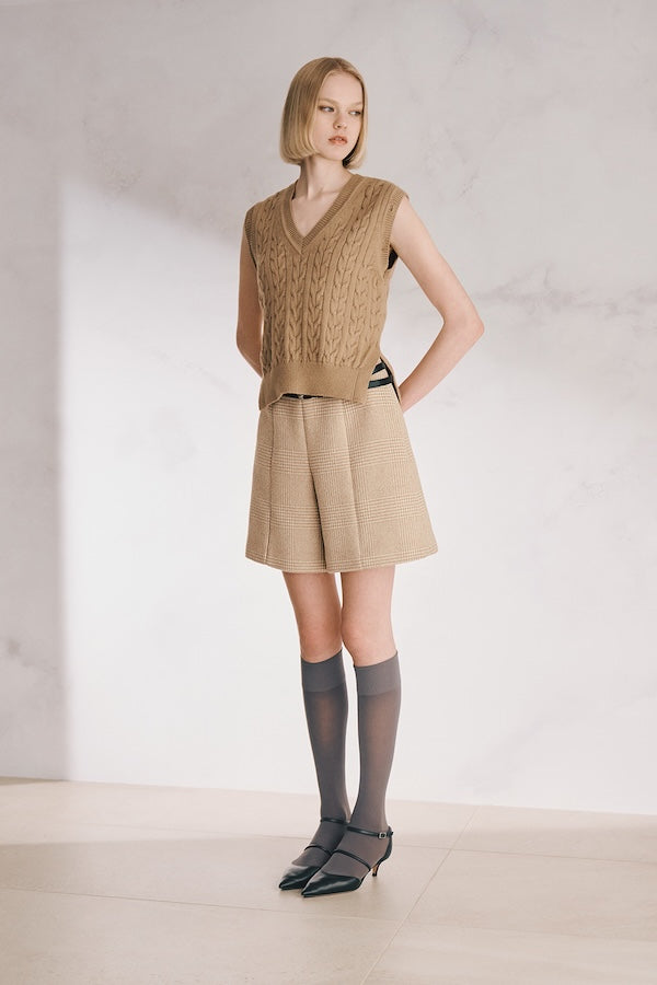 The model is wearing a beige vest and a beige skirt.