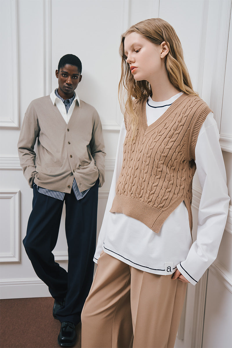 Two models wearing knit vests, cardigans, and wide-leg trousers in neutral colors.
